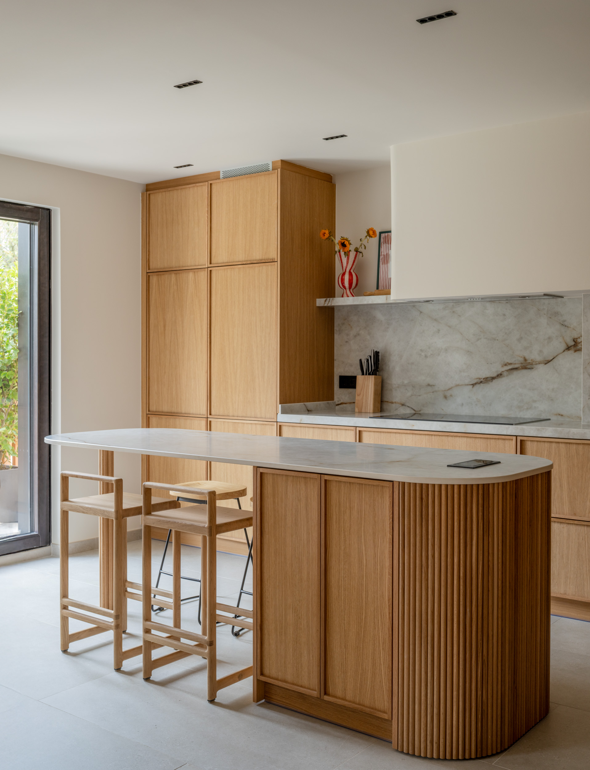 Cocina de madera, mármol blanco y grifería negra